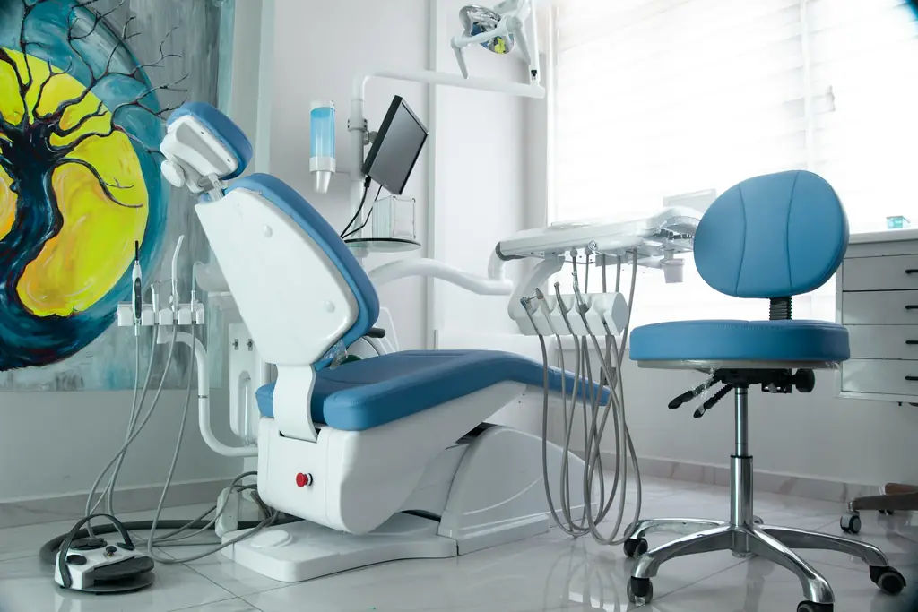 Dental chair and stool with blue upholstery in a bright treatment room